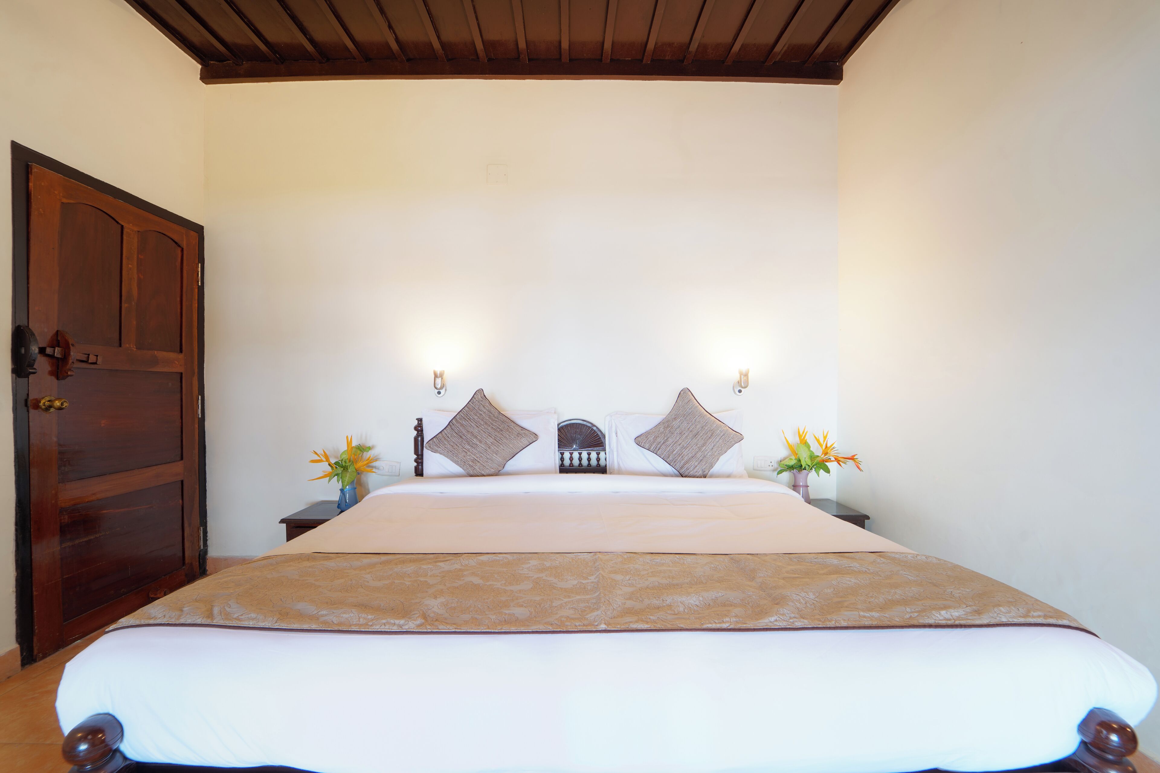 Une chambre à coucher avec un grand lit, une tête de lit en bois, des tables de chevet avec des lampes et une porte en bois.