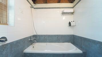 Uma casa de banho moderna com banheira, chuveiro e janela com persianas.