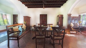 A room with a wooden ceiling, a dining table with chairs, a sofa, and a cabinet. - Alaya Stays by ELIVAAS Vembanad House  (Cherthala)
