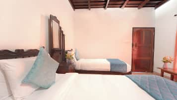 A bedroom with two beds, a wooden headboard, a bedside table with a mirror, and a door.