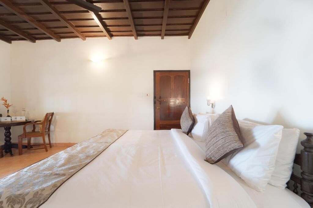 Ein Schlafzimmer mit einem Bett, einer Holztür, einem Schreibtisch mit Stuhl und einer Lampe.