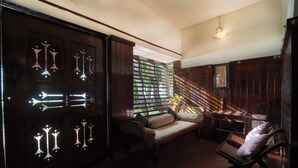A room with a wooden door, a sofa, a bench, and a staircase. - Alaya Stays by ELIVAAS Vembanad House  (Cherthala)