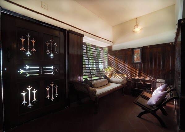 A room with a wooden door, a sofa, a bench, and a staircase.