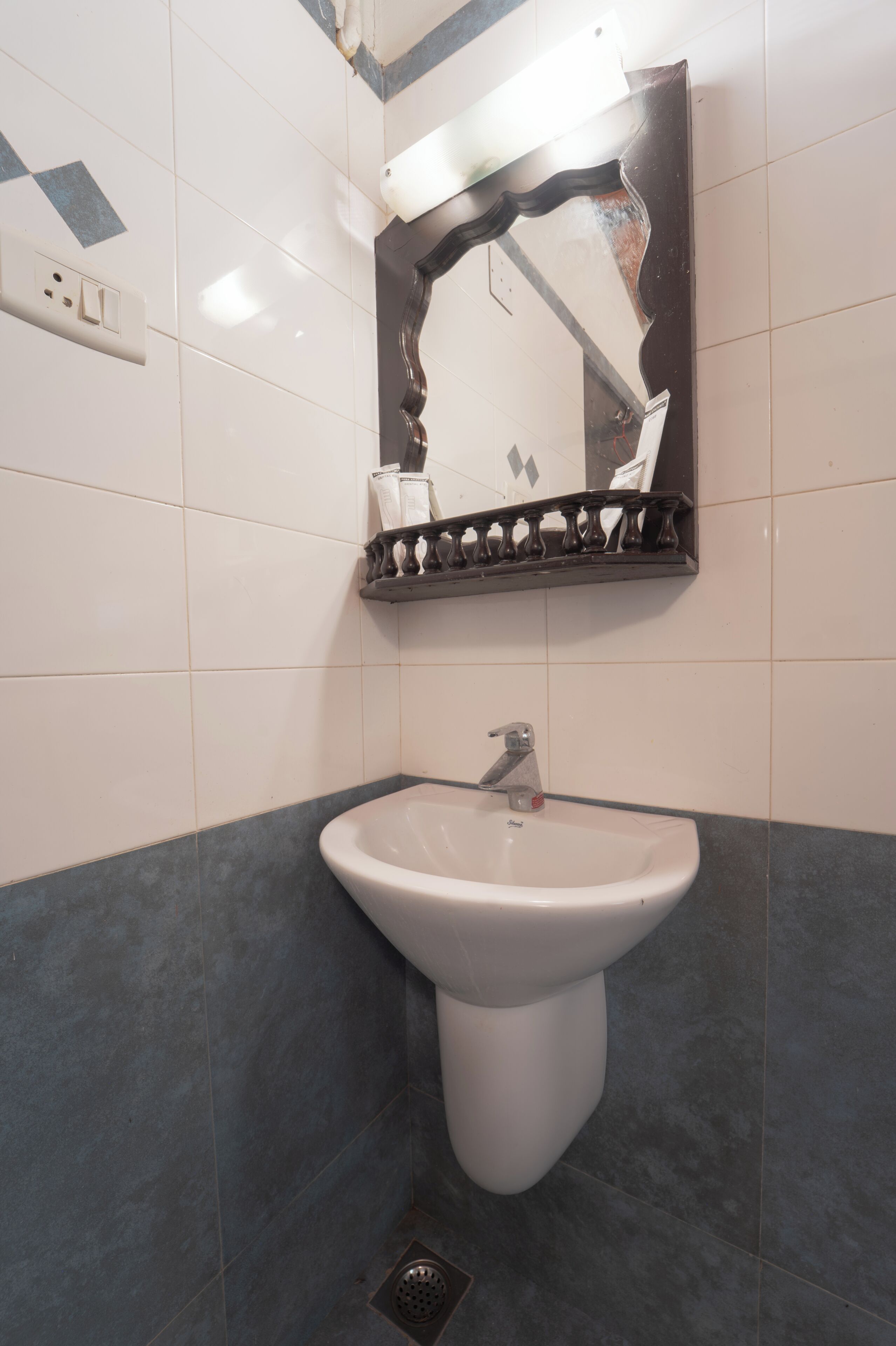 A bathroom with a white sink, a mirror, and a tiled wall.