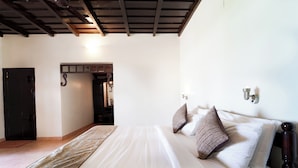 A bedroom with a bed, pillows, a wooden headboard, a door, and a ceiling with wooden beams. - Alaya Stays by ELIVAAS Vembanad House  (Cherthala)