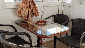 Ein Essbereich mit einem Tisch aus Glas, Korbstühlen und einem gemusterten Vorhang.