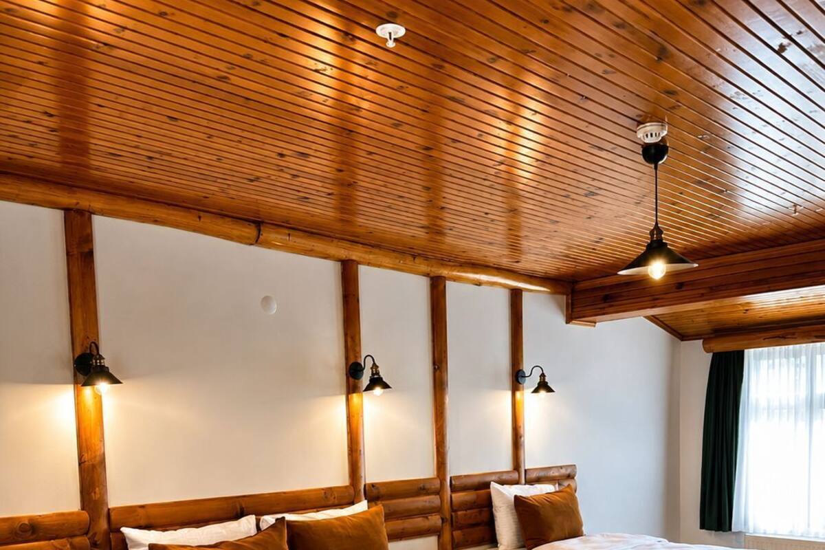 Una habitación con dos camas, vigas de madera en el techo e iluminación empotrada en la pared.
