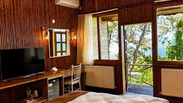 Una habitación de madera con una cama, un televisor, un escritorio y una ventana con vistas.