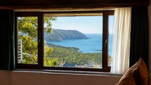 Ein Schlafzimmer mit großem Fenster und Blick auf eine Küstenlandschaft.