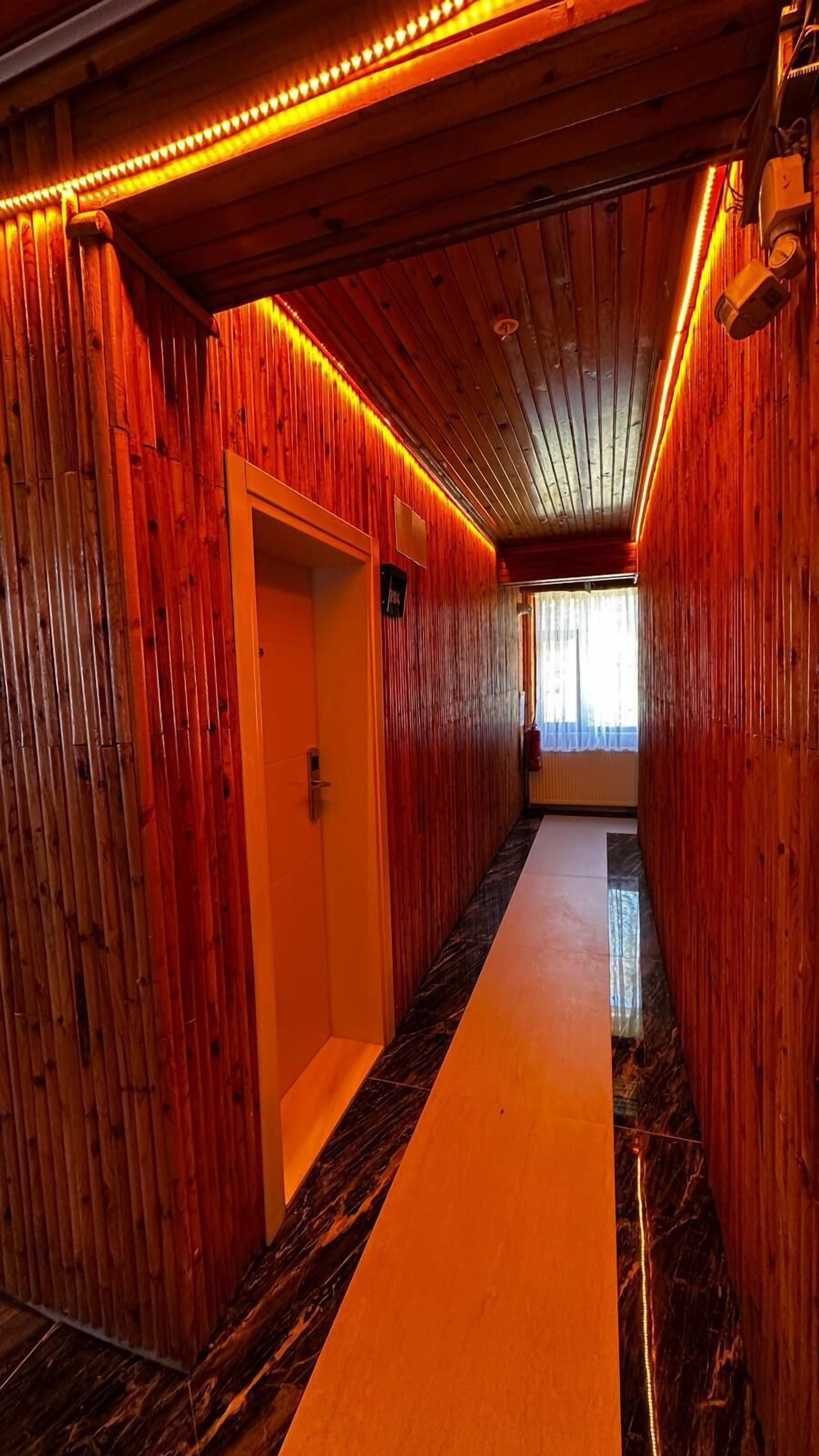 A corridor with wooden walls and a marble floor, leading to a door.