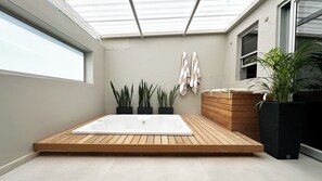 A modern bathroom with a wooden deck, a large bathtub, and potted plants. - Modern Hideaway with Jacuzzi & Fireplace (Cape Town)