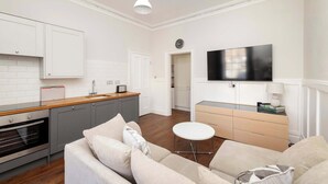 A modern kitchen with grey cabinets, a wooden countertop, and a built-in oven. - Stylish West End 1-Bed | Prime Location (Edinburgh)