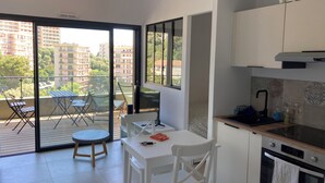 A modern kitchen with a dining area, large windows, and a balcony with outdoor furniture. - Superb studio with sea view of downtown Bastia  (Bastia)