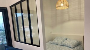 A bedroom with a bed, a TV, and a window with a view of buildings. - Superb studio with sea view of downtown Bastia  (Bastia)