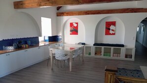 Una cocina con comedor, armarios blancos y techo de madera.