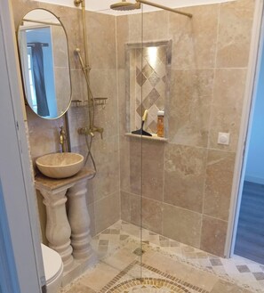 Une salle de bain avec un lavabo sur pied, un miroir, une douche avec une paroi en verre et un carrelage décoratif.