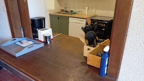 Una cocina con encimera de madera, cafetera, tostadora, lavavajillas y estufa.