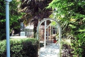 A garden with a stone pathway leading to a glass structure, surrounded by lush greenery. - Quaint 8-bedroom house in Villepinte perfect for group stays (Villepinte)