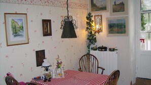 Un coin repas avec une nappe à carreaux, des chaises en bois, des œuvres d’art accrochées au mur et un luminaire suspendu.
