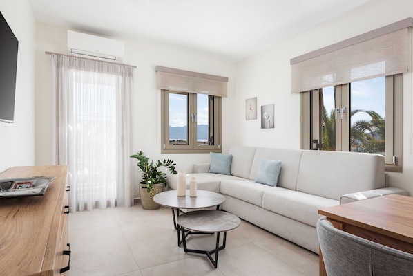 A modern living room with a sofa, two round tables, a TV, and a window with a view.
