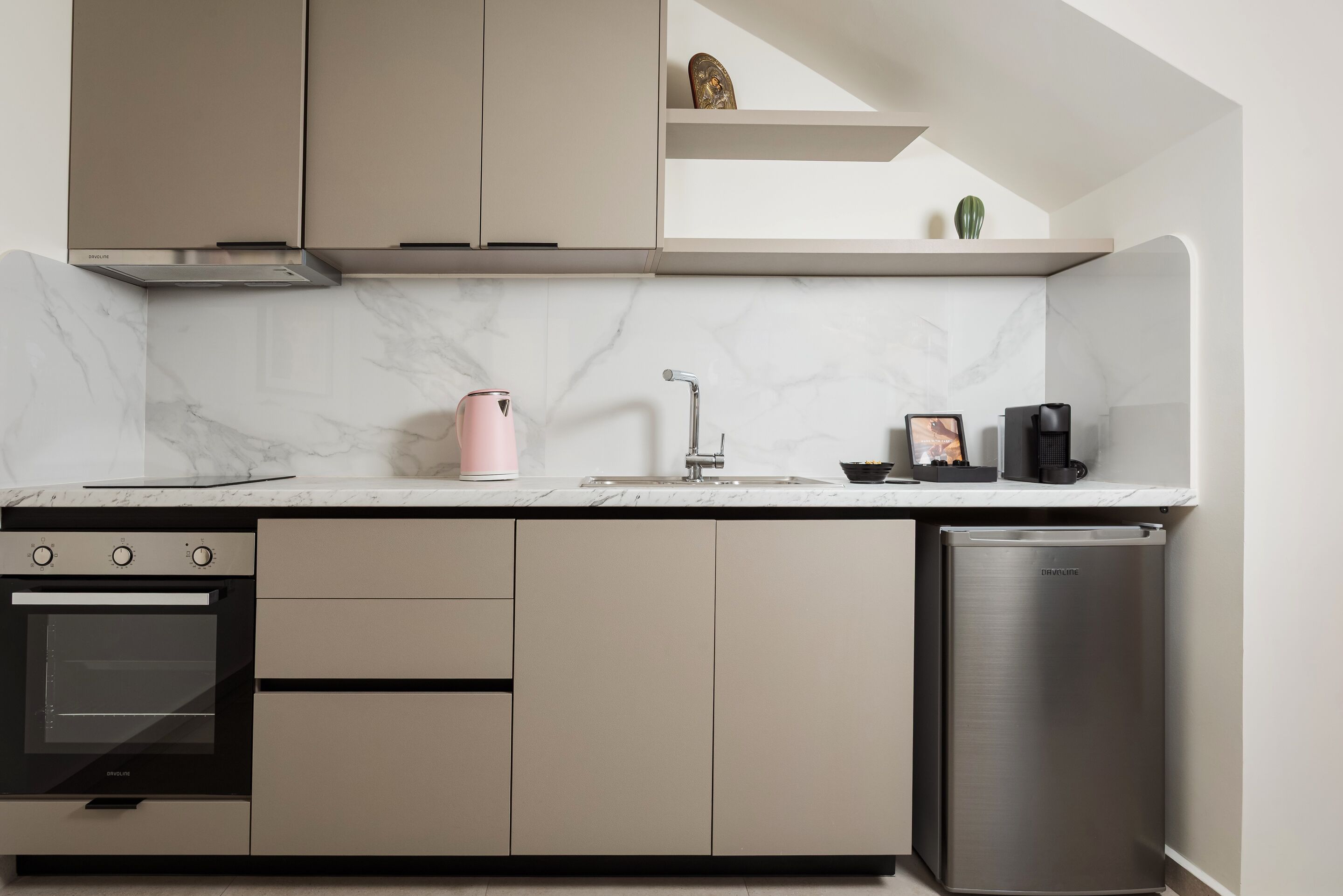 A modern kitchen with built-in appliances, a marble countertop, and a minimalist design.