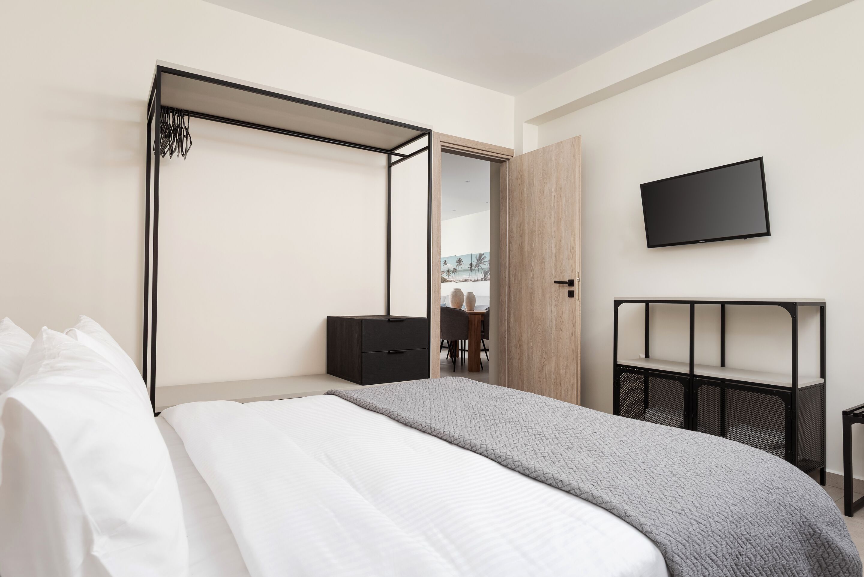 Une chambre d’hôtel moderne équipée d’un lit, d’une télévision, d’une armoire et d’un bureau.