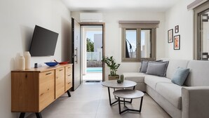 Una sala de estar moderna con un sofá, una mesa de centro, un televisor en la pared y un mueble de madera.