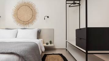 A bedroom with a bed, bedside tables, a wall-mounted light, a mirror, and a black wardrobe.
