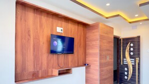 A reception area with a wooden panel wall, a mounted television, and a door with a decorative design. - Hotel BN Palace  (Barakpur)