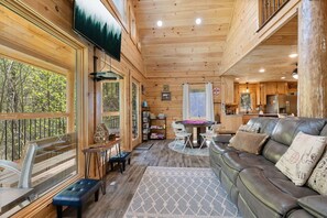 A cabin interior with a dining area, a sofa, and a kitchen. - Mountain Wolf’s Cabin: Family Fun Near Downtown (Gatlinburg)