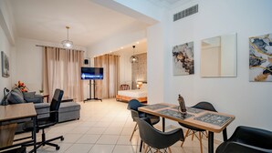 Een moderne woonkamer met een televisie, bank, eettafel, stoelen en kunstwerken aan de muur.