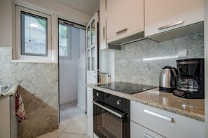 Eine Küche mit Granit-Arbeitsplatten, einem Einbauofen, einer Kaffeemaschine und einem Fenster mit Jalousien.