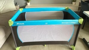 Ein Trampolin mit 'Dream n Play'-Branding, ein an der Wand befestigter Flachbildfernseher und ein Blumentopf auf dem Boden.
