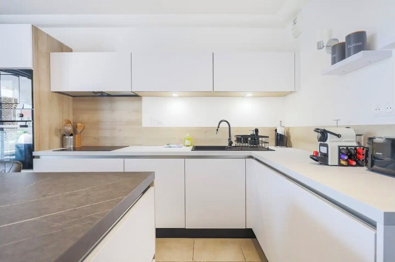 A modern kitchen with white cabinets, a dark countertop, and a built-in oven.