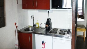 A compact kitchen with a refrigerator, stove, sink, and red cabinets. - 2 Rooms for 6 People (Huez)