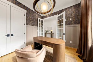Une pièce comprenant un bureau, une chaise, une armoire et une porte à panneaux de verre.