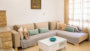 Een woonkamer met een hoekbank, een witte salontafel en een decoratief stenen object.