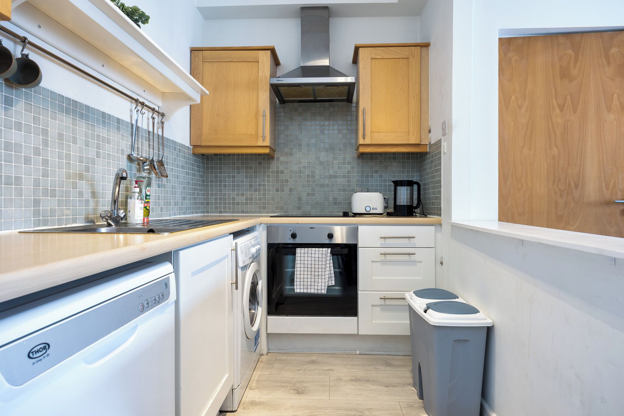 A compact kitchen with a dishwasher, oven, and a coffee maker.