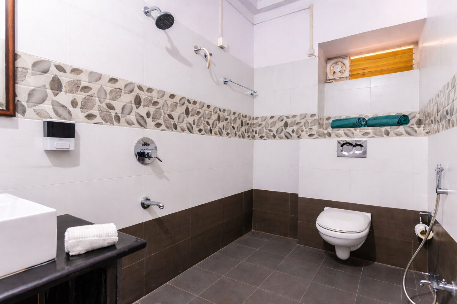 Een badkamer met toilet, wastafel, douche en handdoekhouder.