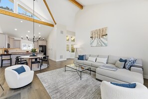 A spacious living area with a high ceiling, a dining area, and a kitchen with modern appliances. - Relaxing Summer Getaway by InvitedHome | Hot Tub, Bunk Room, Fitness, Fireplace (Park City)