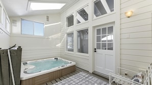 Un jacuzzi en un espacio exterior cubierto con vistas a la casa.