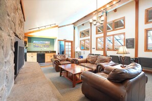 A spacious living area with leather sofas, a wooden coffee table, and a kitchen in the background. - Mountainside Mt. Royal Condo - Stunning Views, Great Year-Round Location! (Frisco)