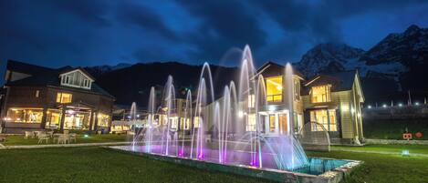 Un hotel con una fuente, asientos al aire libre y vistas a la montaña.