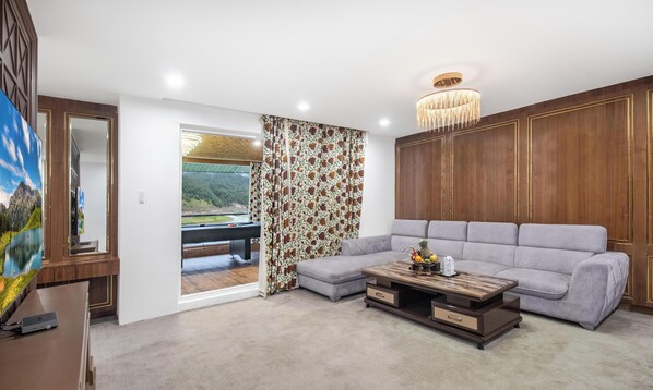 Uma sala de estar moderna com um sofá, uma mesa de centro e vista para uma paisagem montanhosa através de uma grande janela.