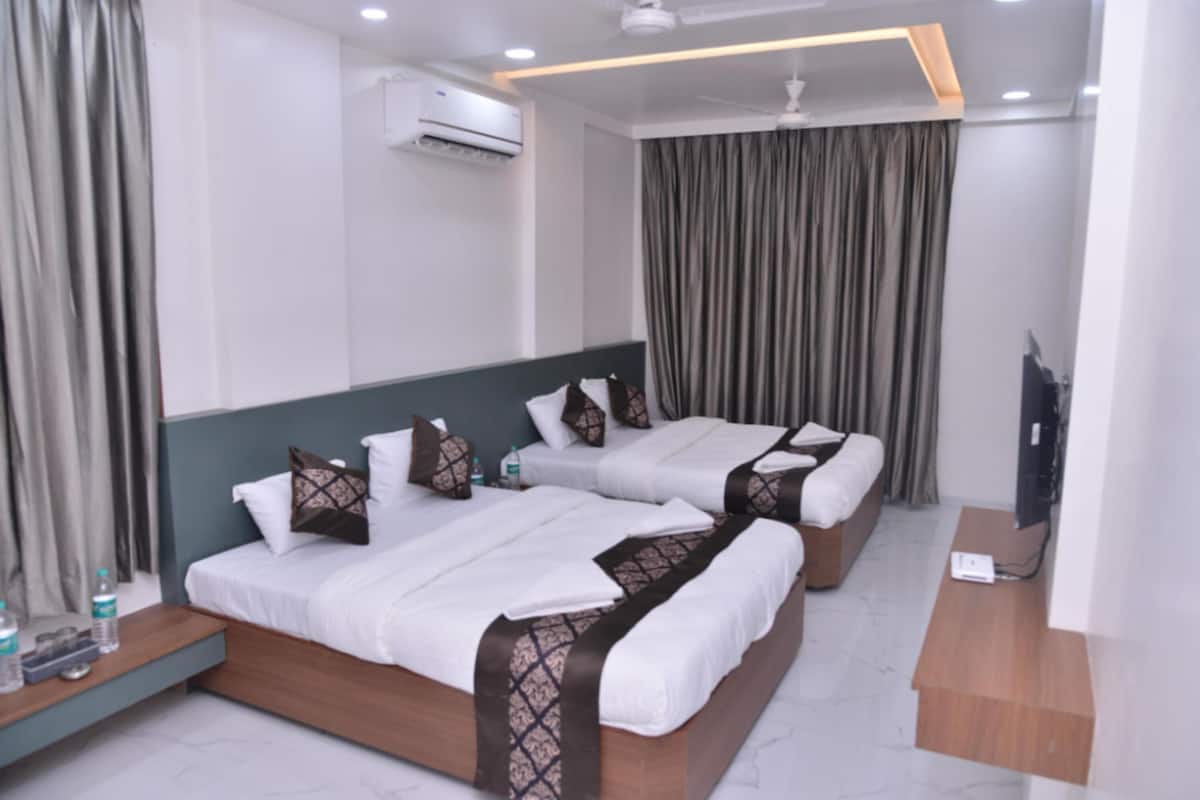 A hotel room with two beds, a flat-screen TV, a ceiling fan, and an air conditioning unit.