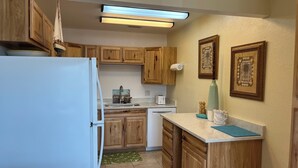Eine Küche mit Holzschränken, einem Kühlschrank, einer Spüle, einem Toaster und einer Wandleuchte.
