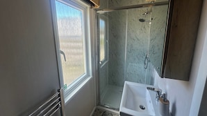 A bathroom with a shower, a sink, and a window. - Self-catering Lodge Inverness - Sleeps 4 (Inverness)