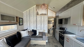 A compact living space with a sofa, patterned cushions, a kitchen area, and a patterned floor. - Self-catering Lodge Inverness - Sleeps 4 (Inverness)