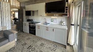 Een moderne keuken met witte kasten, een zwarte kookplaat en een groot raam.