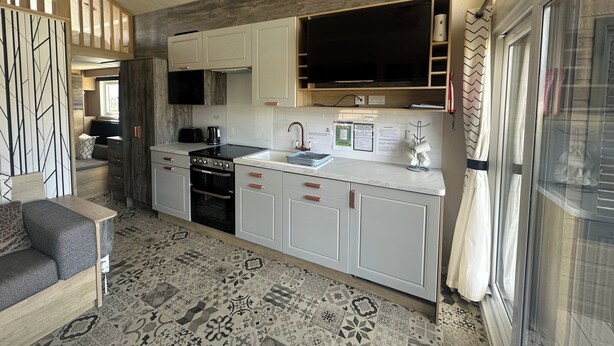 A modern kitchen with white cabinets, a black stove, and a large window. - Self-catering Lodge Inverness - Sleeps 4 (Inverness)